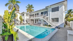 Un edificio moderno con piscina, escaleras y palmeras.