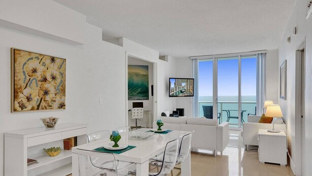 Ein moderner, offener Wohn- und Essbereich mit Balkon und Meerblick.