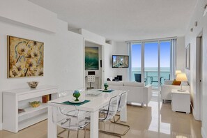 A modern, open-plan living and dining area with a balcony overlooking the sea.