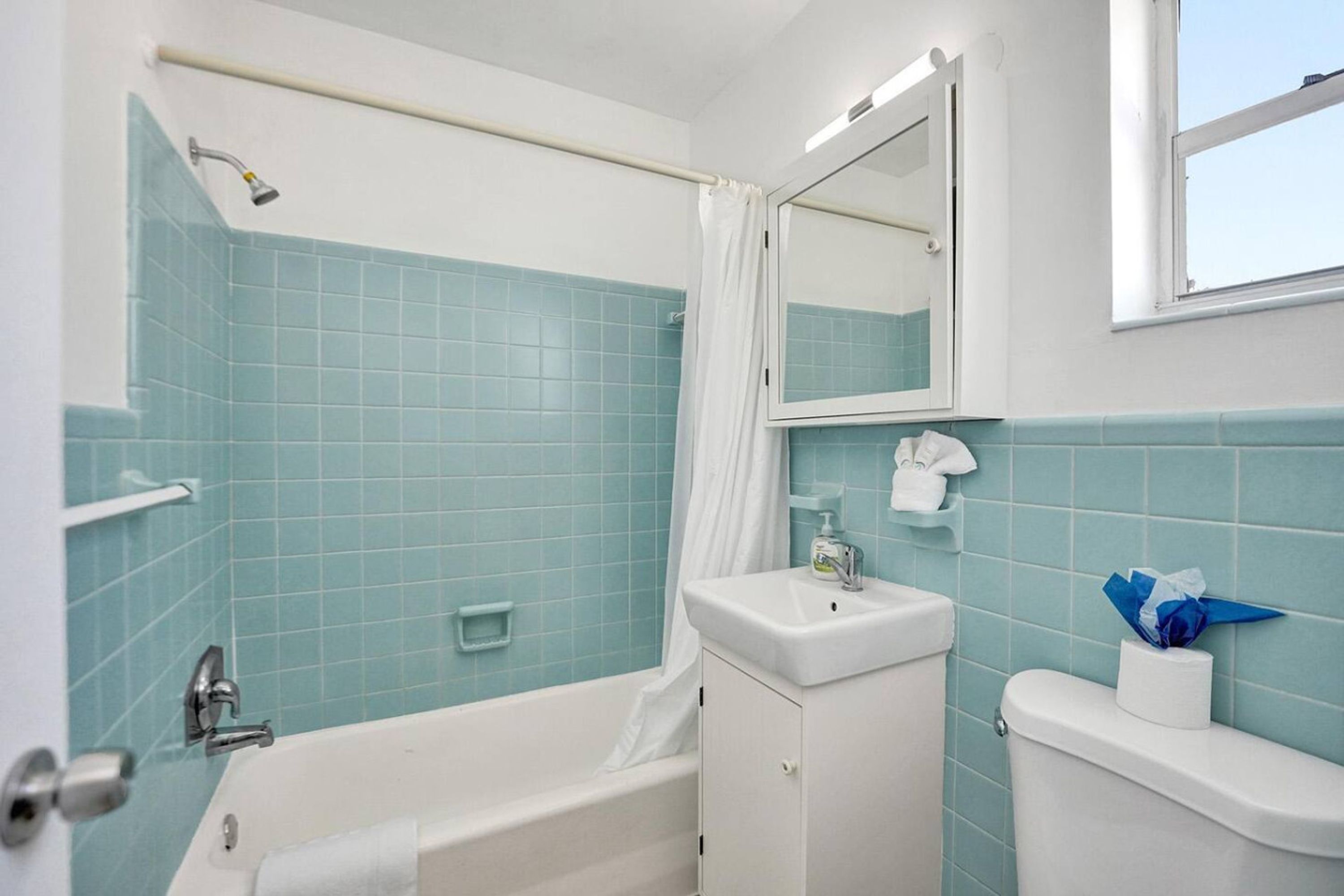 Een badkamer met een bad, een wastafel, een toilet en een spiegel.