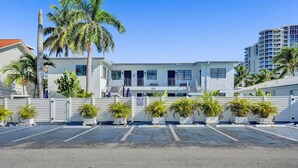 A hotel with a white facade, multiple balconies, and a parking lot with potted plants. - Waves on Desoto Beautiful Studio (Hollywood)