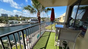 A balcony with a view of a marina, a palm tree, and a red umbrella. - Beautiful Water View Golden Isles (Hallandale Beach)