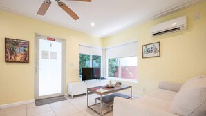 Una sala de estar con un sofá, una mesa de centro, un televisor y una puerta con la leyenda 'EXIT'.