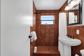 A bathroom with a shower, a sink, a mirror, and a window. - Waves On Walnut 4-beach Access (Hollywood)