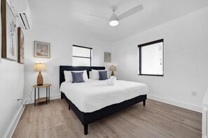 A bedroom with a bed, two bedside tables, a ceiling fan, and two windows with blinds. - Waves On Walnut 4-beach Access (Hollywood)