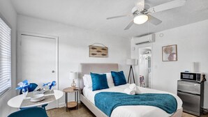 A neatly arranged bedroom with a bed, bedside table, and a small desk with a chair. - Waves on Desoto Beautiful Studio 7 (Hollywood)