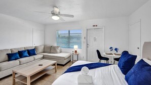 Une chambre d’hôtel comprenant un lit, un canapé, une table basse, un bureau avec une lampe et un ventilateur de plafond.