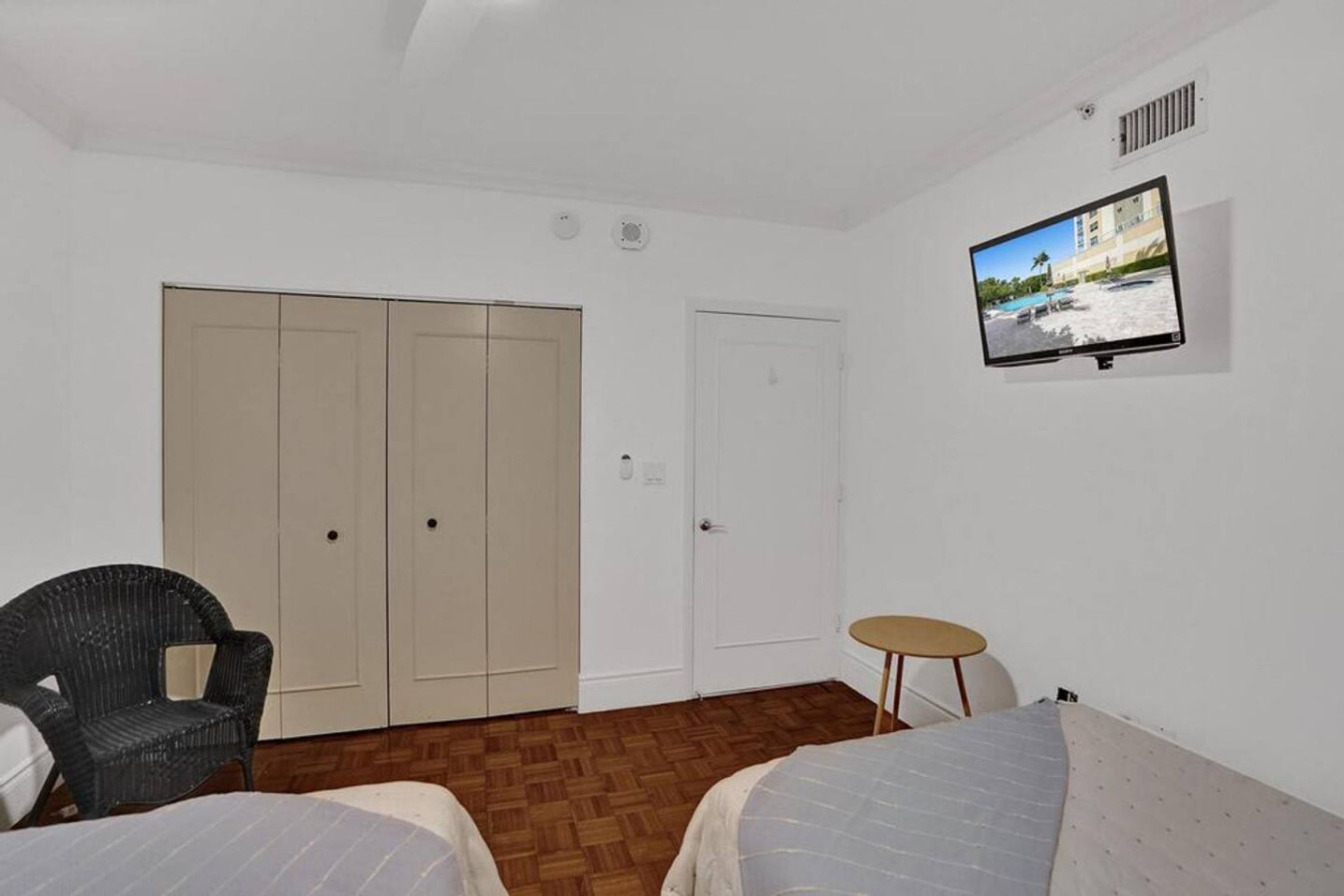 Une chambre avec deux lits, une chaise, un téléviseur et une armoire.