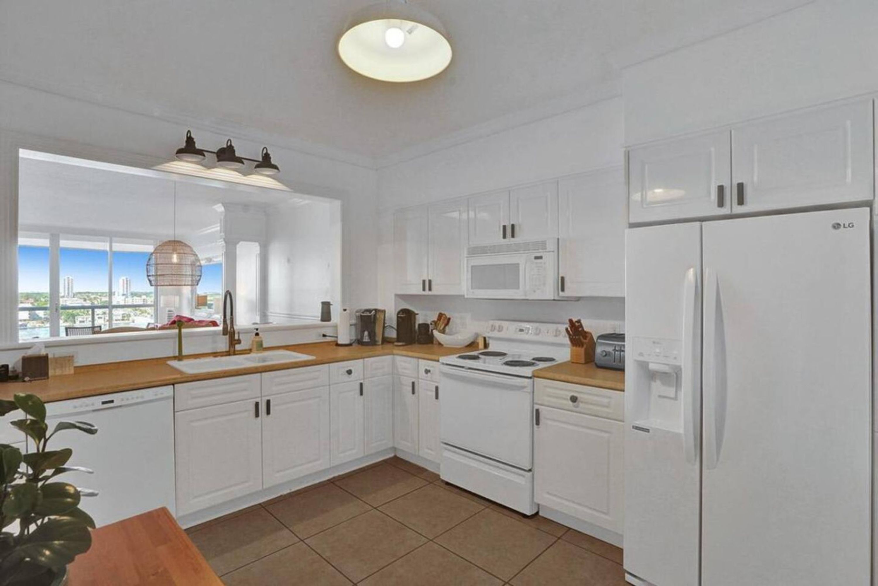 A modern kitchen with white cabinetry, a stove, microwave, and refrigerator.