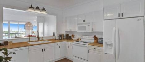 A modern kitchen with white cabinetry, a stove, microwave, and refrigerator.