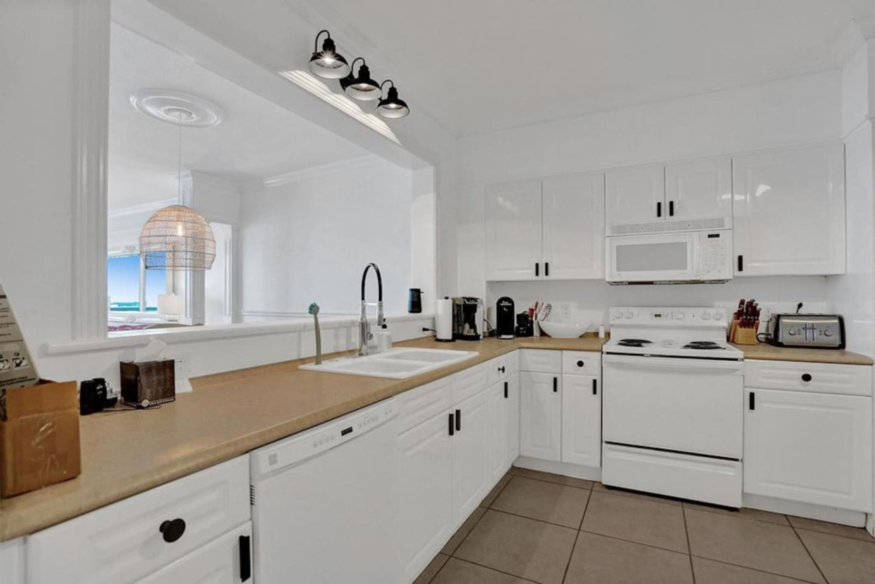 Una cocina moderna con armarios blancos, encimera de madera, microondas integrado, estufa y ventana con vistas.