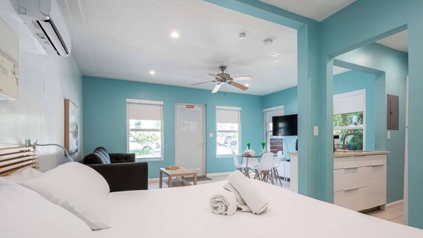 A hotel room with a bed, a desk, a chair, a sofa, a ceiling fan, and a kitchenette. - Casa Del Mar Deluxe Studio 2 (Hollywood)