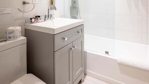 A modern bathroom with a toilet, sink, mirror, shower, and bathtub. - Casa Del Mar Deluxe Studio 2 (Hollywood)