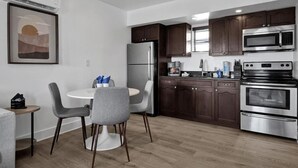 Una cocina moderna con gabinetes de madera oscura, electrodomésticos de acero inoxidable y una mesa de comedor redonda con sillas.