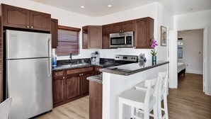 Una cocina moderna con armarios de madera, electrodomésticos de acero inoxidable y una isla central con asientos.