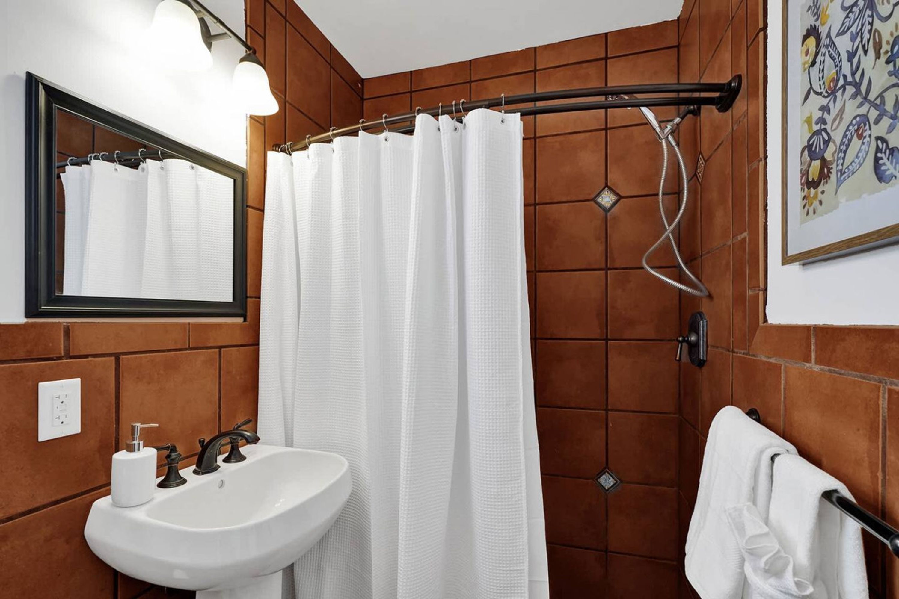 A bathroom with a white sink, a mirror, a shower curtain, and a towel rack.