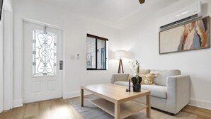 A modern living room with a wooden coffee table, a grey sofa, a floor lamp, and a painting on the wall. - Waves On Walnut 2-beach Access (Hollywood)