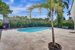 Una piscina rodeada por un patio empedrado, con una palmera al frente.