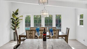 Comedor con mesa de mármol, dos copas de vino, una botella de vino y una planta en maceta.