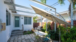 A patio with a table and chairs, a grill, and a covered area with a white awning. - Casa Del Mar 5 Beach Access (Hollywood)