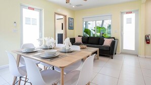 A dining area with a table set for four, white chairs, and a ceiling fan. - Casa Del Mar 5 Beach Access (Hollywood)