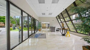 A modern lobby with glass doors, a reception desk, and a large window offering a view of the outdoors. - le Cartier Sunny Isles Ocean Paradise (Sunny Isles Beach)
