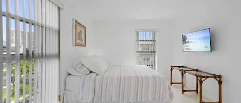 Un dormitorio con cama, televisor y ventana con persianas.