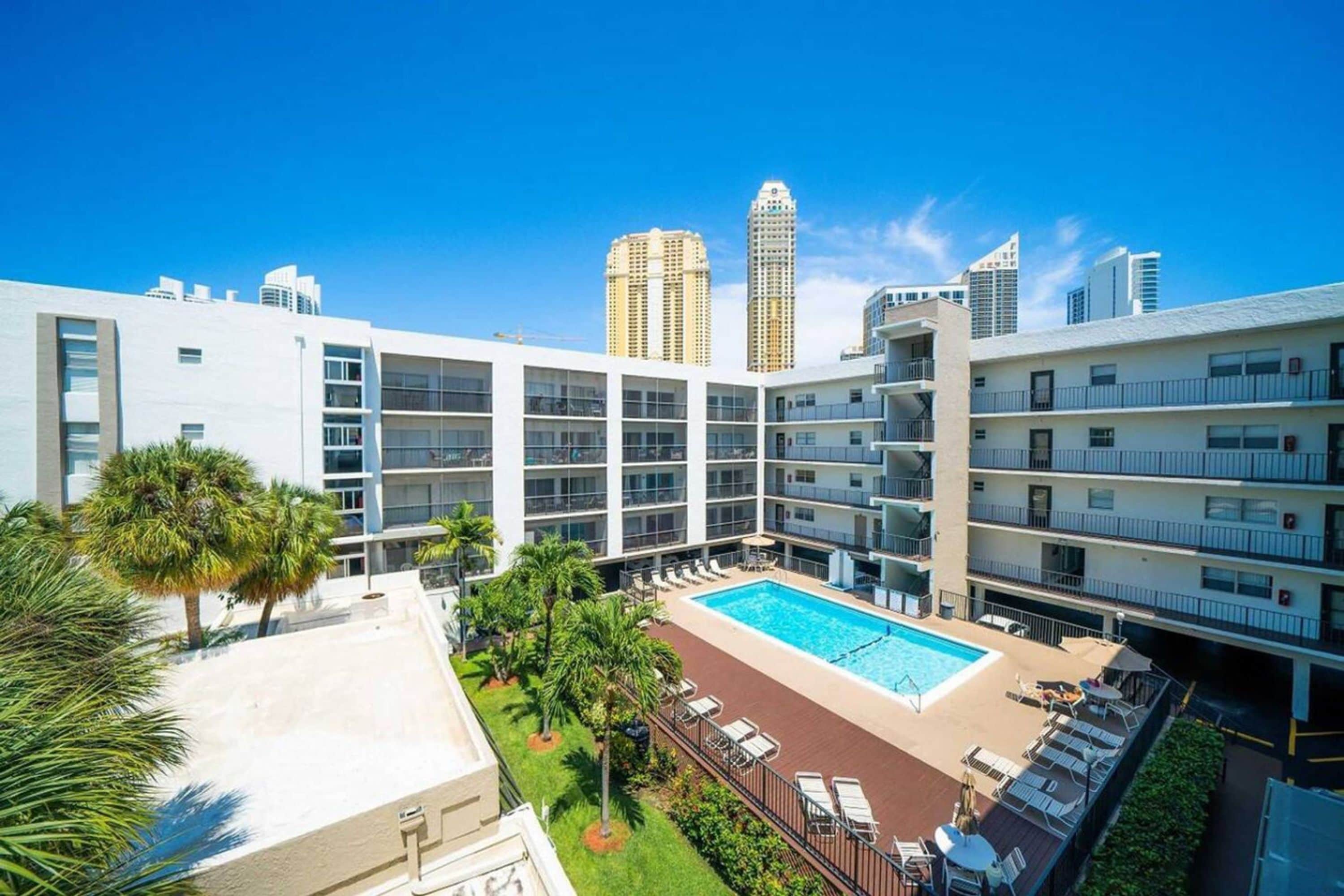 Un hôtel moderne doté d’une piscine sur le toit, de nombreux balcons et offrant une vue sur les immeubles environnants.