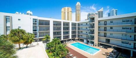 Un hôtel moderne doté d’une piscine sur le toit, de nombreux balcons et offrant une vue sur les immeubles environnants.