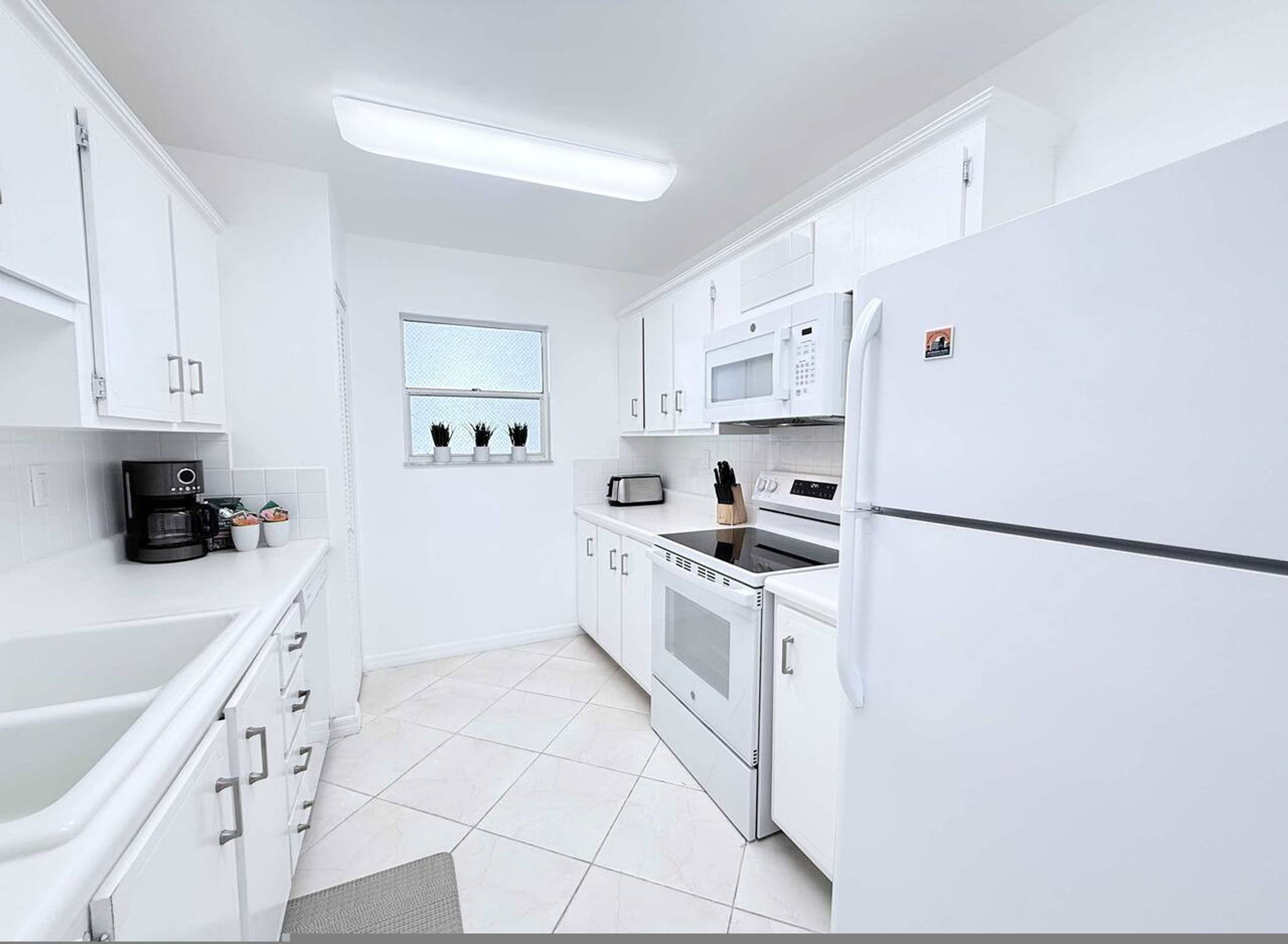 A modern kitchen with white cabinets, a built-in oven, microwave, and refrigerator.