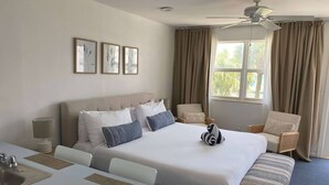 Une chambre d’hôtel avec un grand lit, un bureau, une chaise et une fenêtre avec des rideaux.