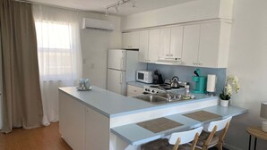 Une cuisine moderne avec des meubles blancs, un îlot central doté de chaises, une cuisinière et un four à micro-ondes.