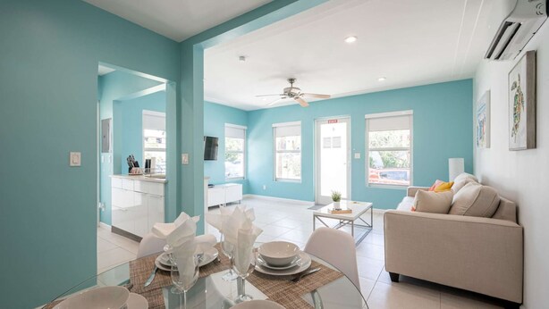 A modern living room with a sofa and a dining area with a glass table and chairs. - Casa Del Mar 4 1 1 Beach Access (Hollywood)