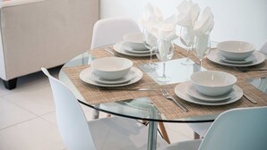 A dining table set with white plates, bowls, and glassware, surrounded by white chairs. - Casa Del Mar 4 1 1 Beach Access (Hollywood)
