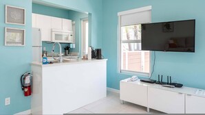 A kitchen with white cabinets, a microwave, a coffee maker, and a sink. There is a fire extinguisher on the wall and a window with a view of the outside. - Casa Del Mar 4 1 1 Beach Access (Hollywood)