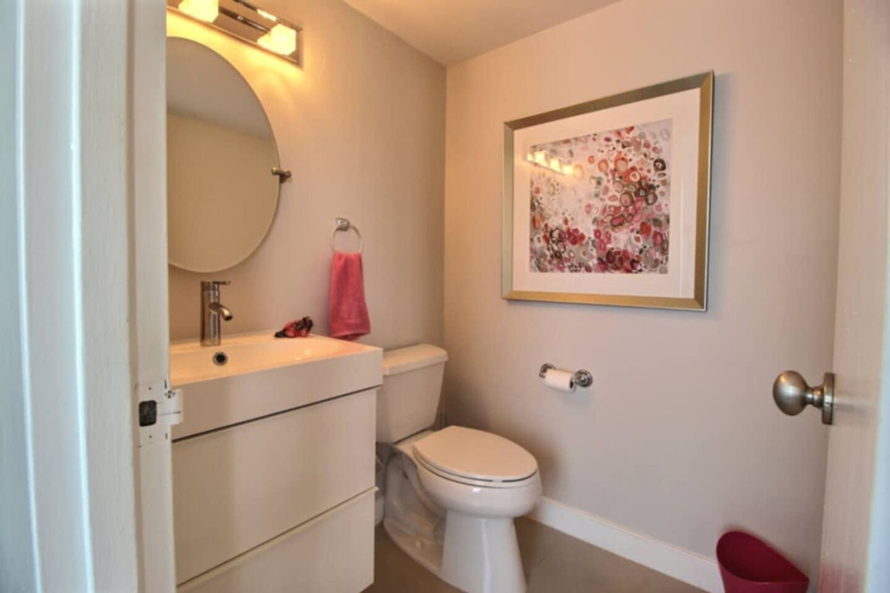 A bathroom with a toilet, sink, and mirror.