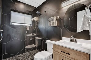 A modern bathroom with a geometric tile design, a large mirror, a toilet, a sink, and a shower. - Hibiscus House in Fort Lauderdale (Fort Lauderdale)