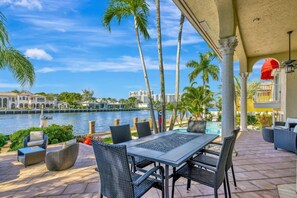 A covered outdoor seating area with a view of a body of water and palm trees. - Serenity Villa Water Front (Lauderdale-by-the-Sea)