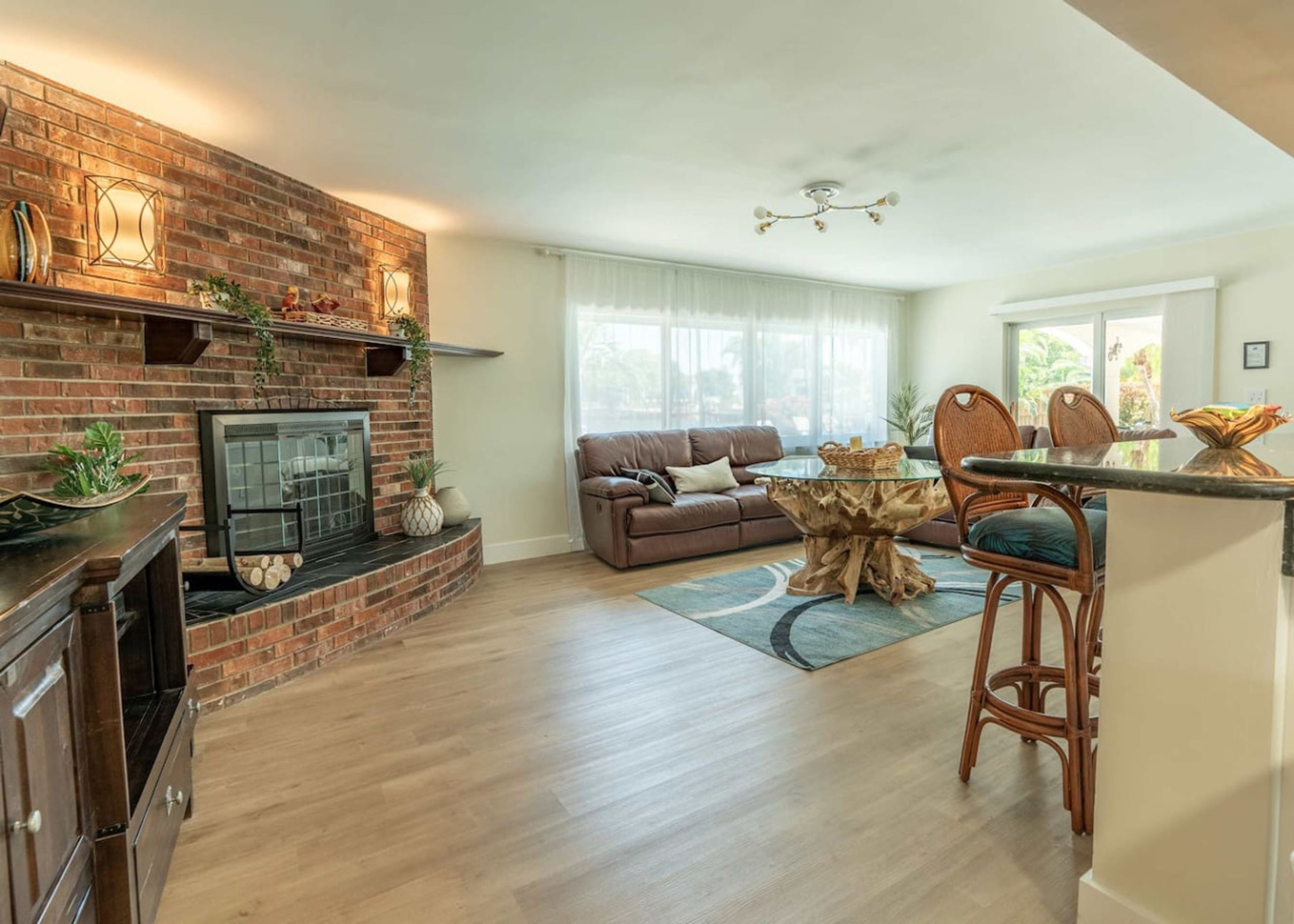 A living room with a brick fireplace, a sofa, a dining table, and a chandelier.