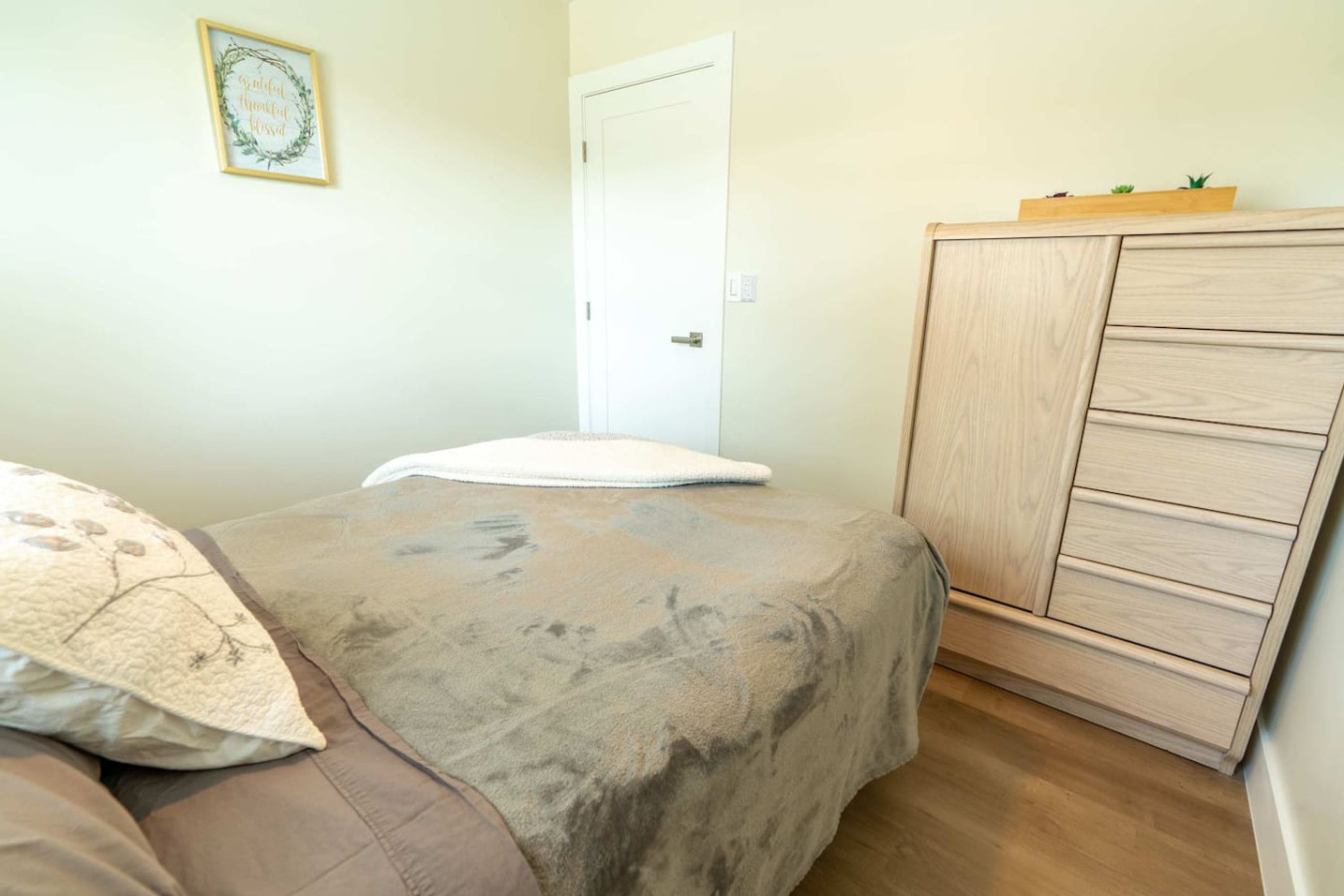 Une chambre à coucher avec un lit, une armoire en bois et une porte.