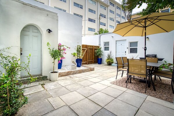 A patio area with a dining table and chairs, a wooden fence, and potted plants.