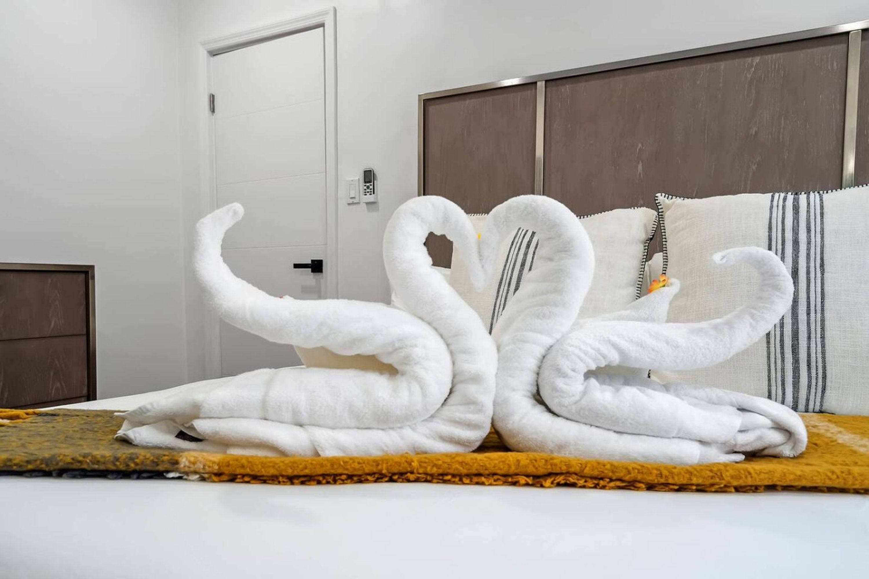 Een bed met een deken met een gele textuur en een witte deur op de achtergrond.