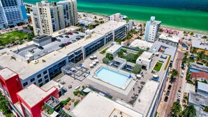 A high-rise hotel with a rooftop pool, a beach view, and multiple amenities including a parking area and outdoor seating. - NEW NEW Ocean Oasis (Hollywood)
