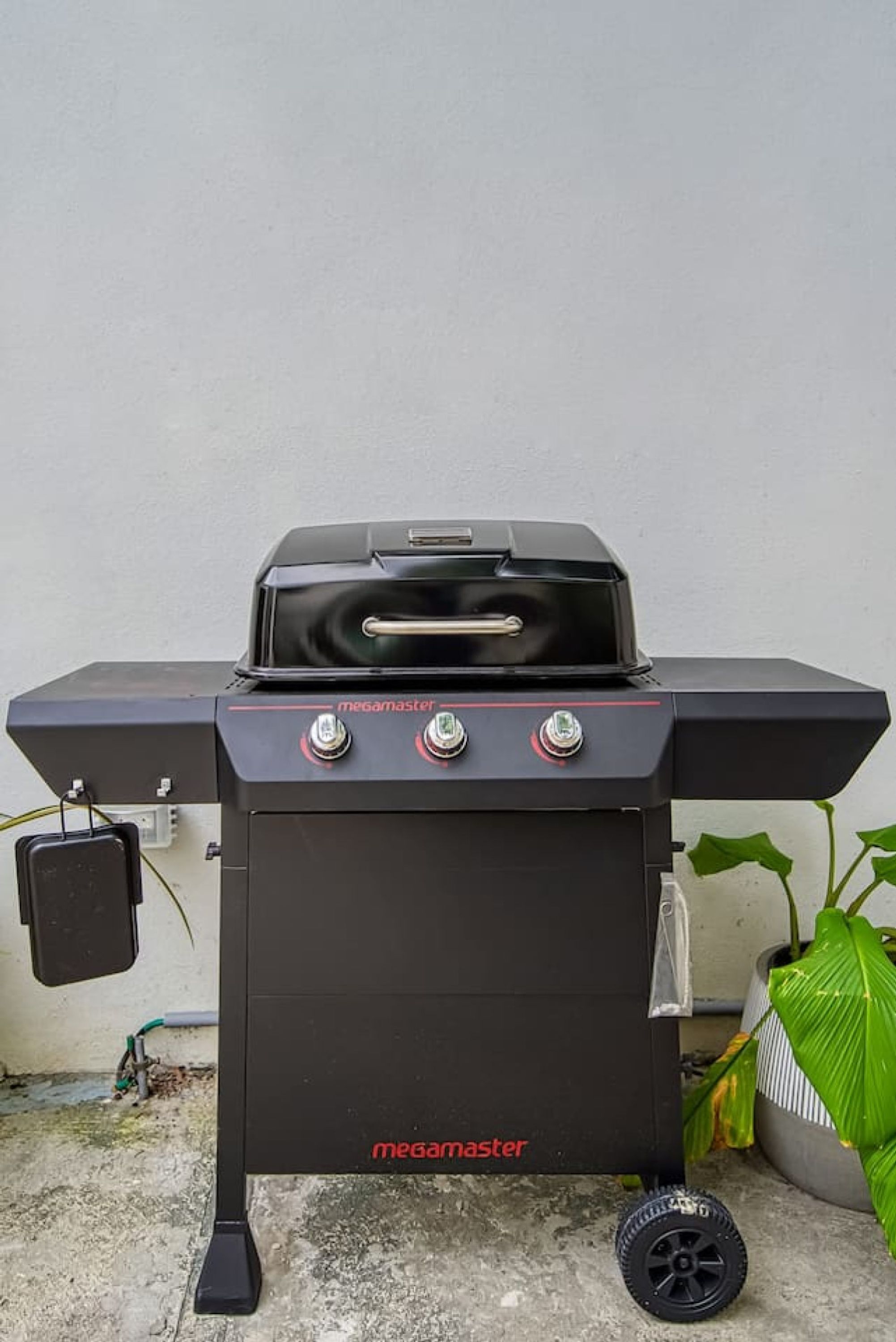 A black outdoor grill with the brand 'megamaster' and a handle on top.