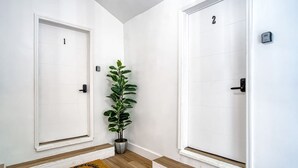 Ein Korridor mit zwei weißen Türen, die mit 1 und 2 nummeriert sind, und einem Blumentopf dazwischen.