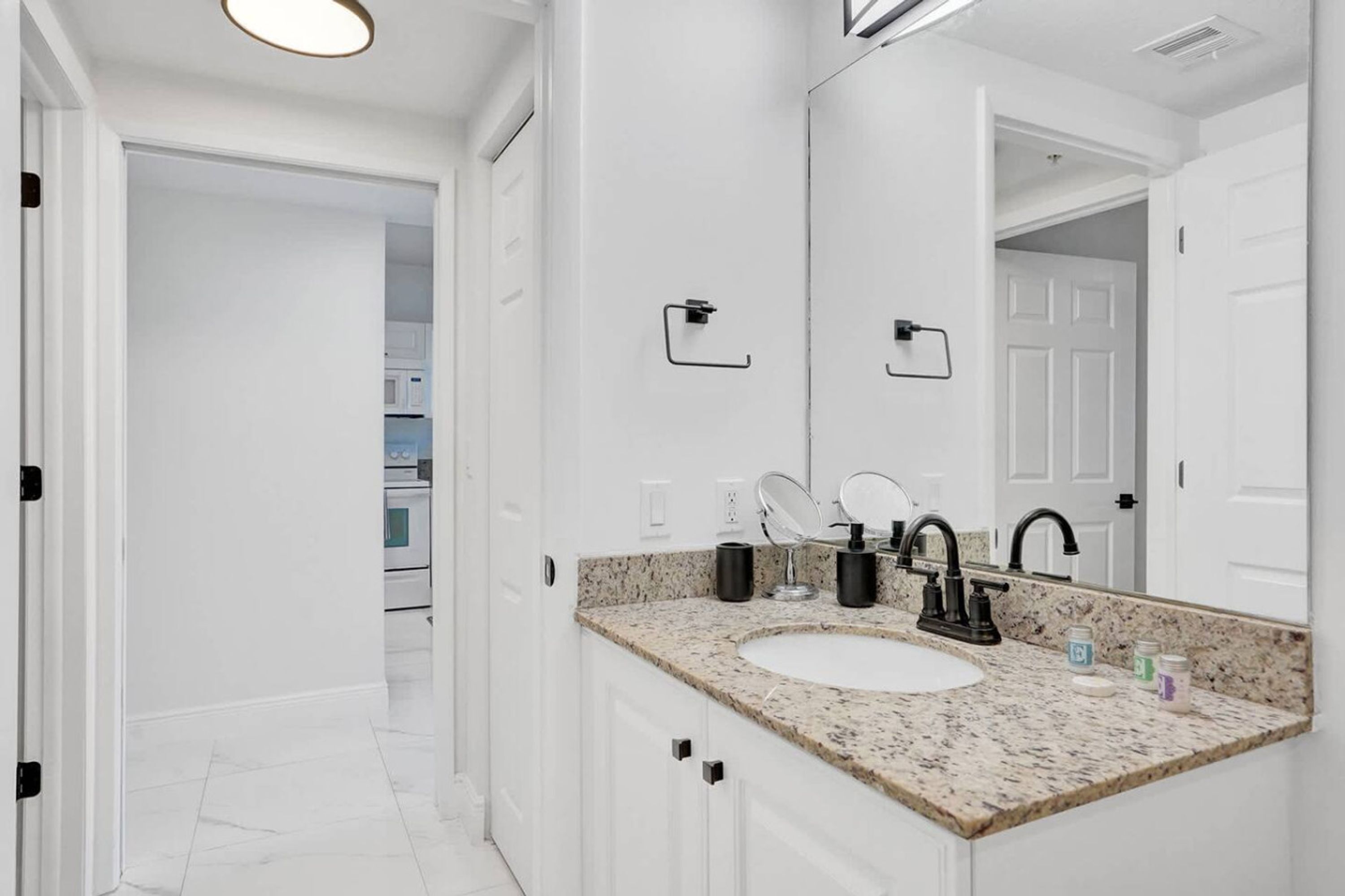 A modern bathroom with a white sink, black faucets, and a granite countertop.