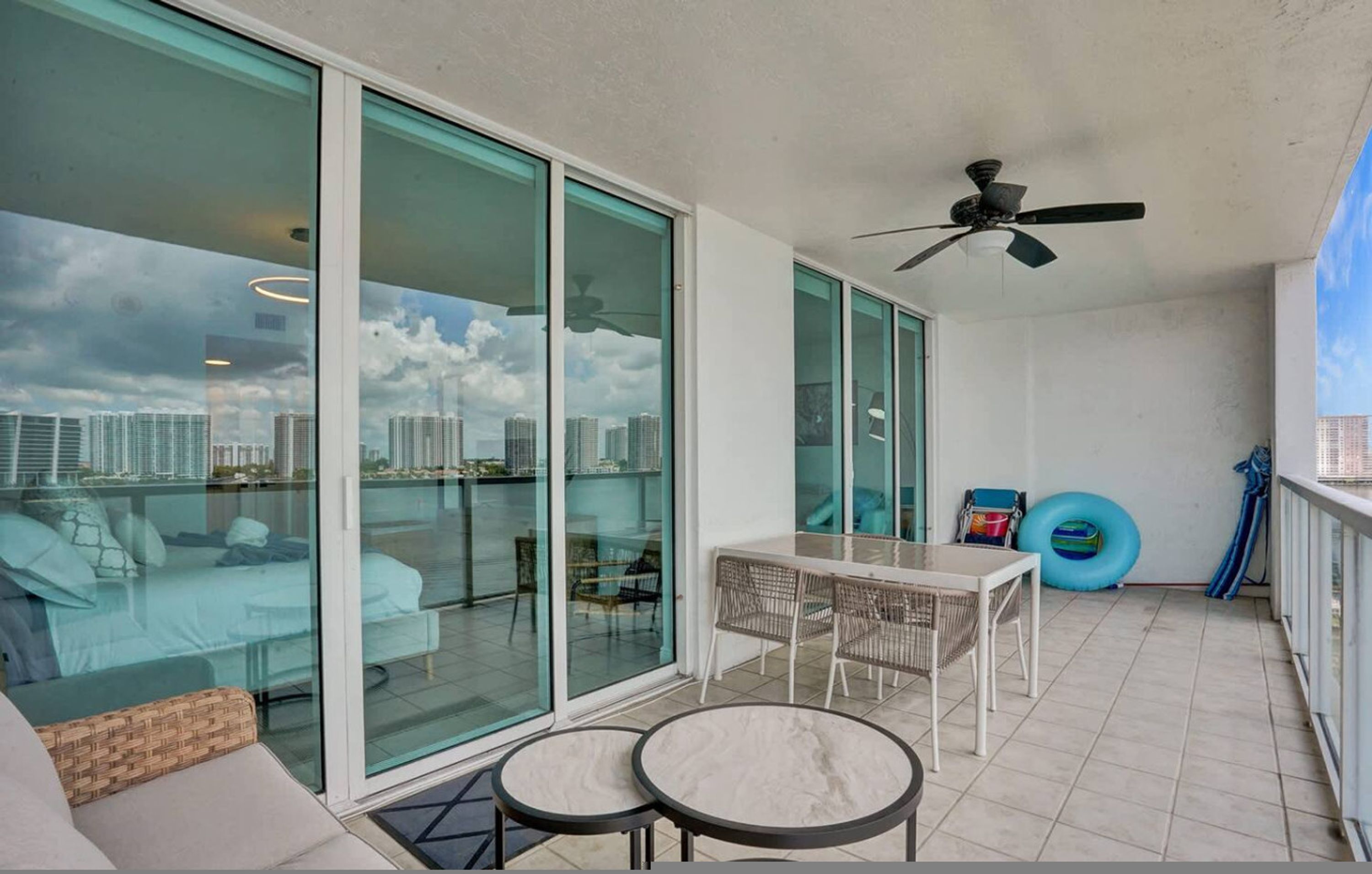 A balcony with a glass door, a ceiling fan, a table, and a chair.
