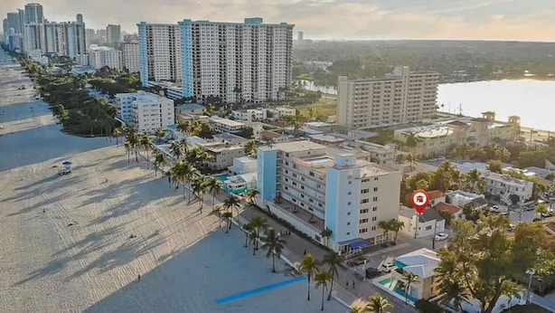 Une vue aérienne d’une ville côtière, avec ses immeubles de grande hauteur, sa plage et un point de repère clairement identifiable.