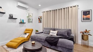 Un salon moderne avec un canapé gris, un fauteuil jaune et une table basse ronde.