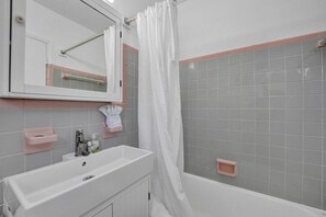 A bathroom with a white sink, mirror, and shower area. - Waves on Desoto Deluxe Studio 4 (Hollywood)